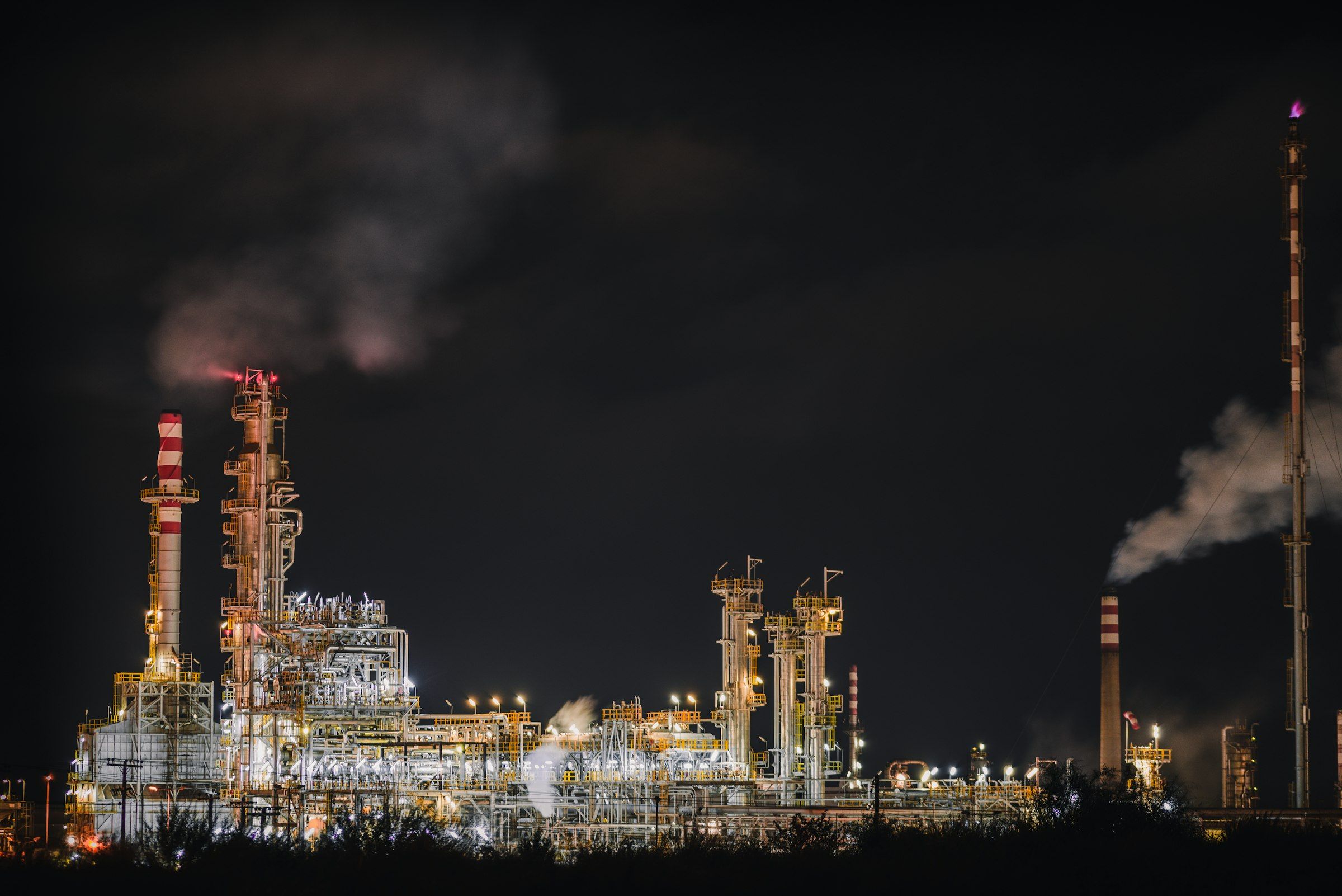 Oil refinery towers at night used for refinery equipment health monitoring