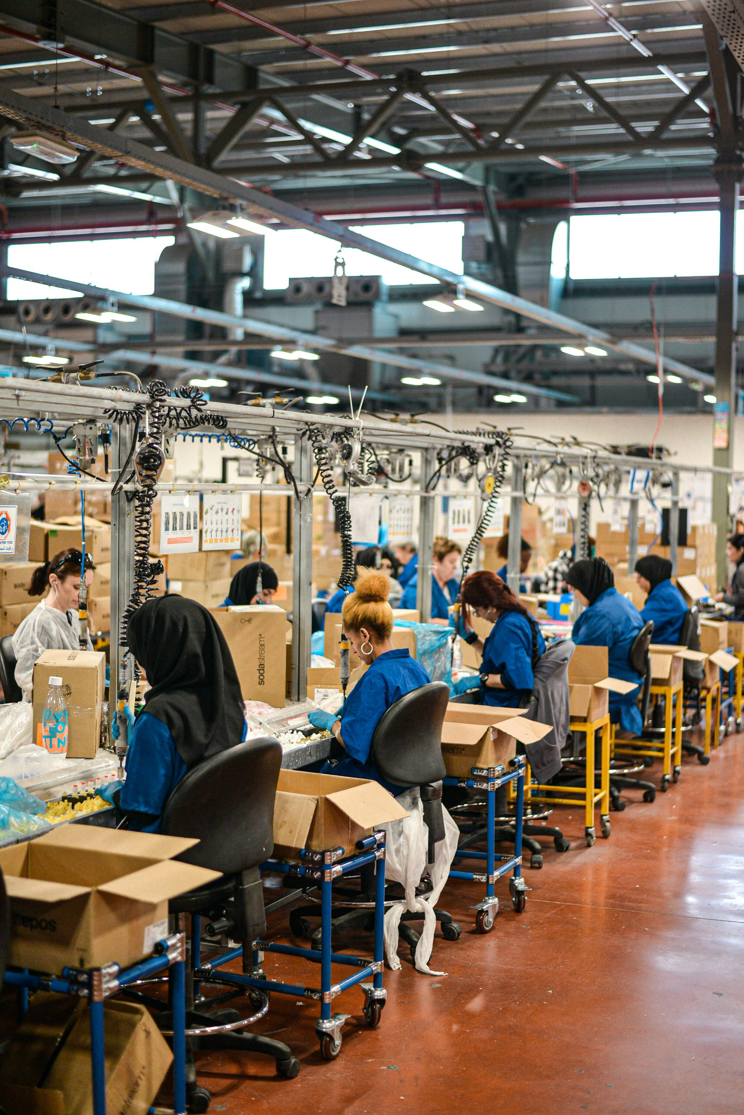 Workers in blue uniforms at an assembly line in a large factory