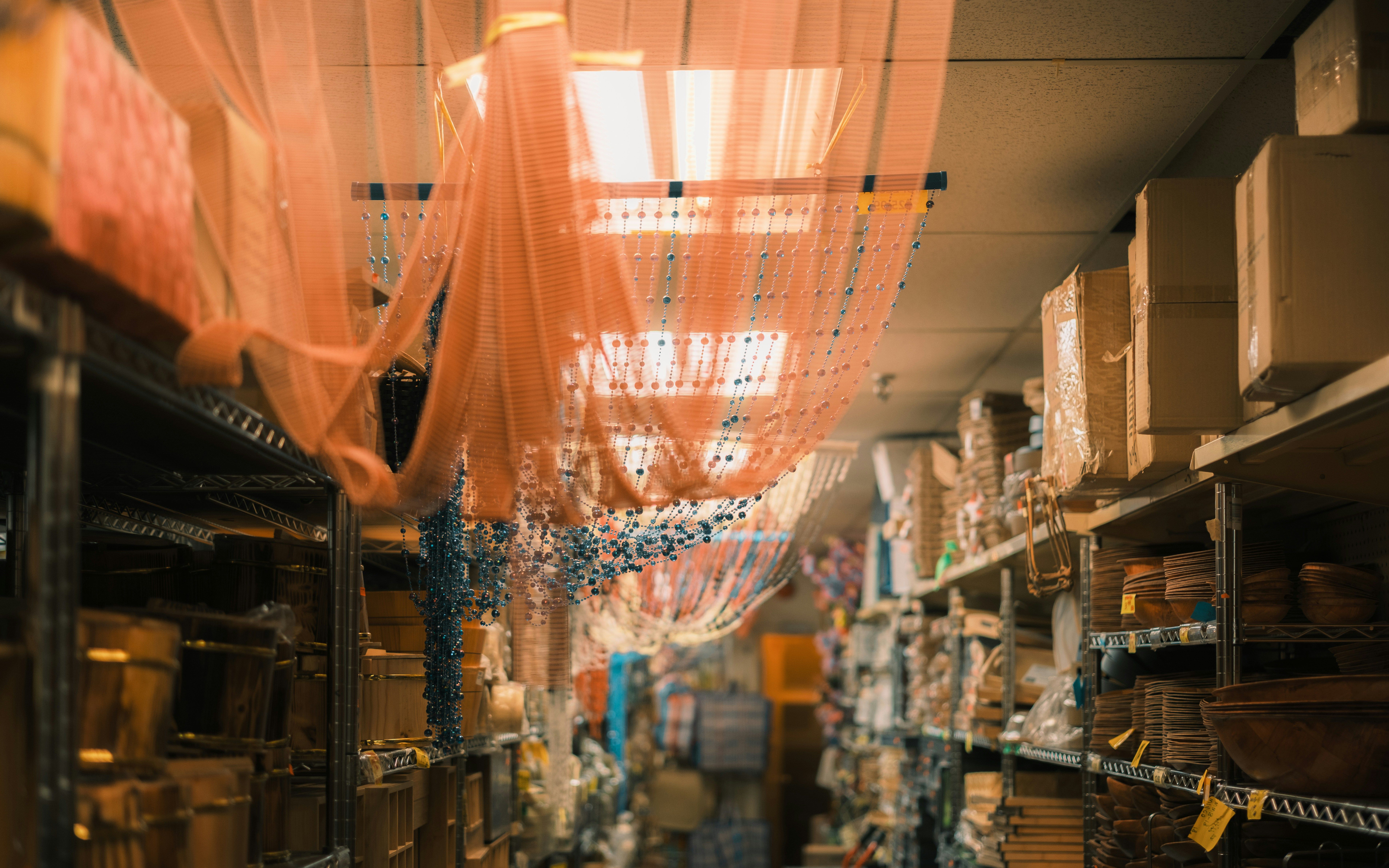 Crowded store aisle with metal shelves stacked with boxes and baskets